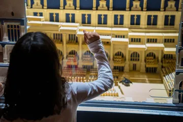 Uma criança toca o vidro que separa a maquete tátil do público.