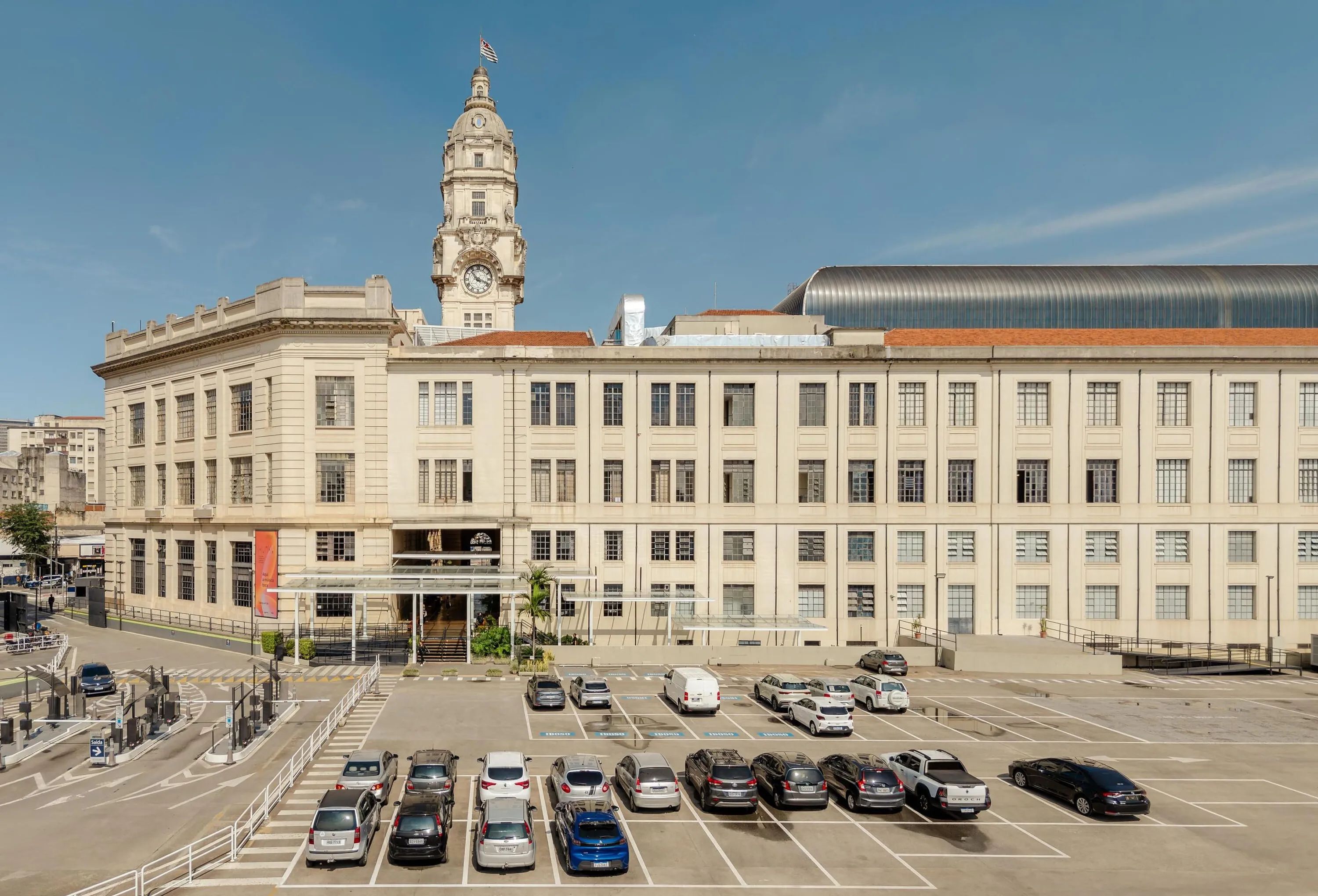O estacionamento é uma grande área de concreto com pinturas no chão que organizam o espaço para os carros. A portaria do estacionamento conta com grandes catracas de pagamento e uma rampa circular que leva ao primeiro e segundo subsolos.