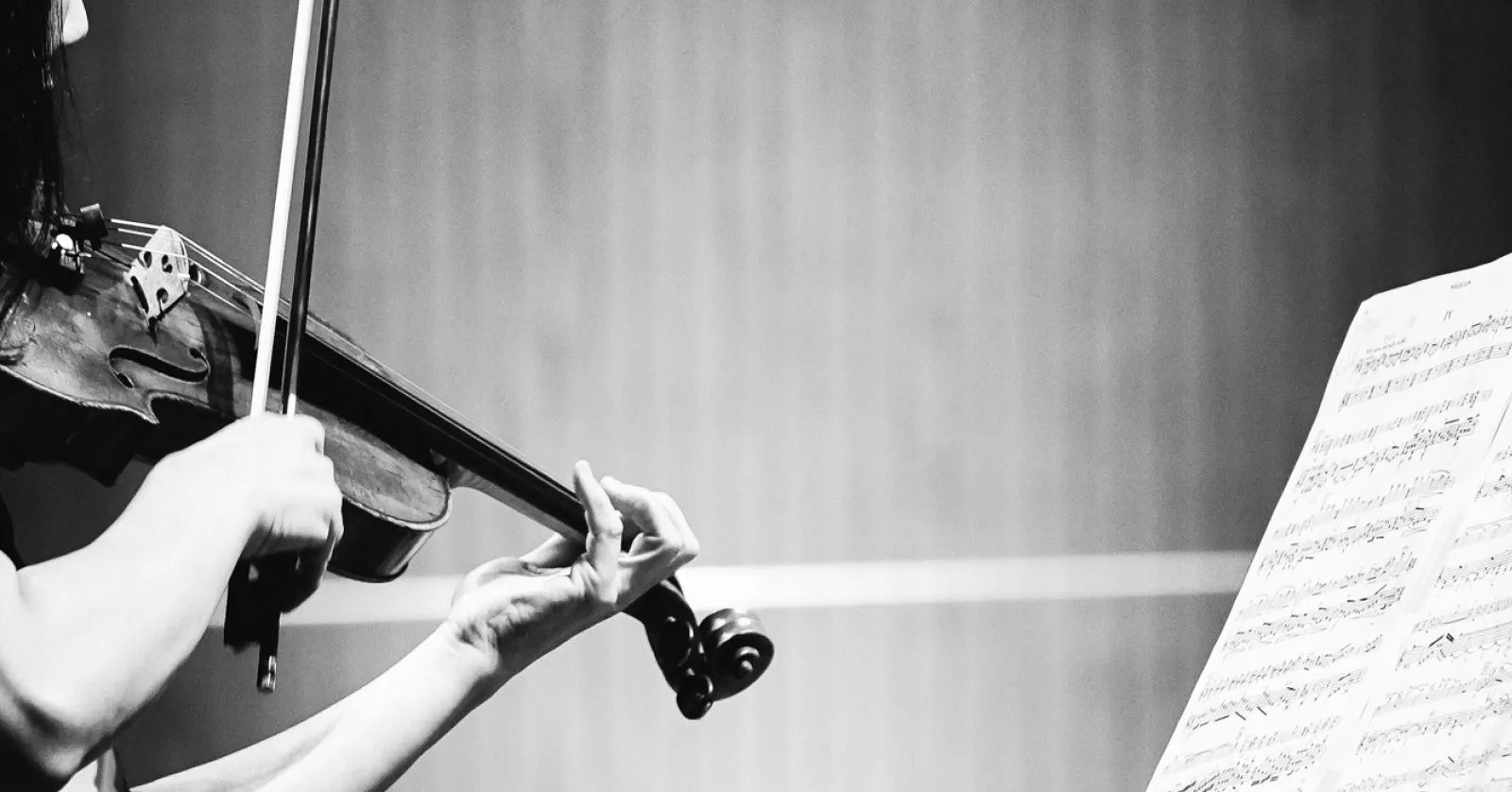 A imagem mostra uma pessoa tocando violino e uma partitura.