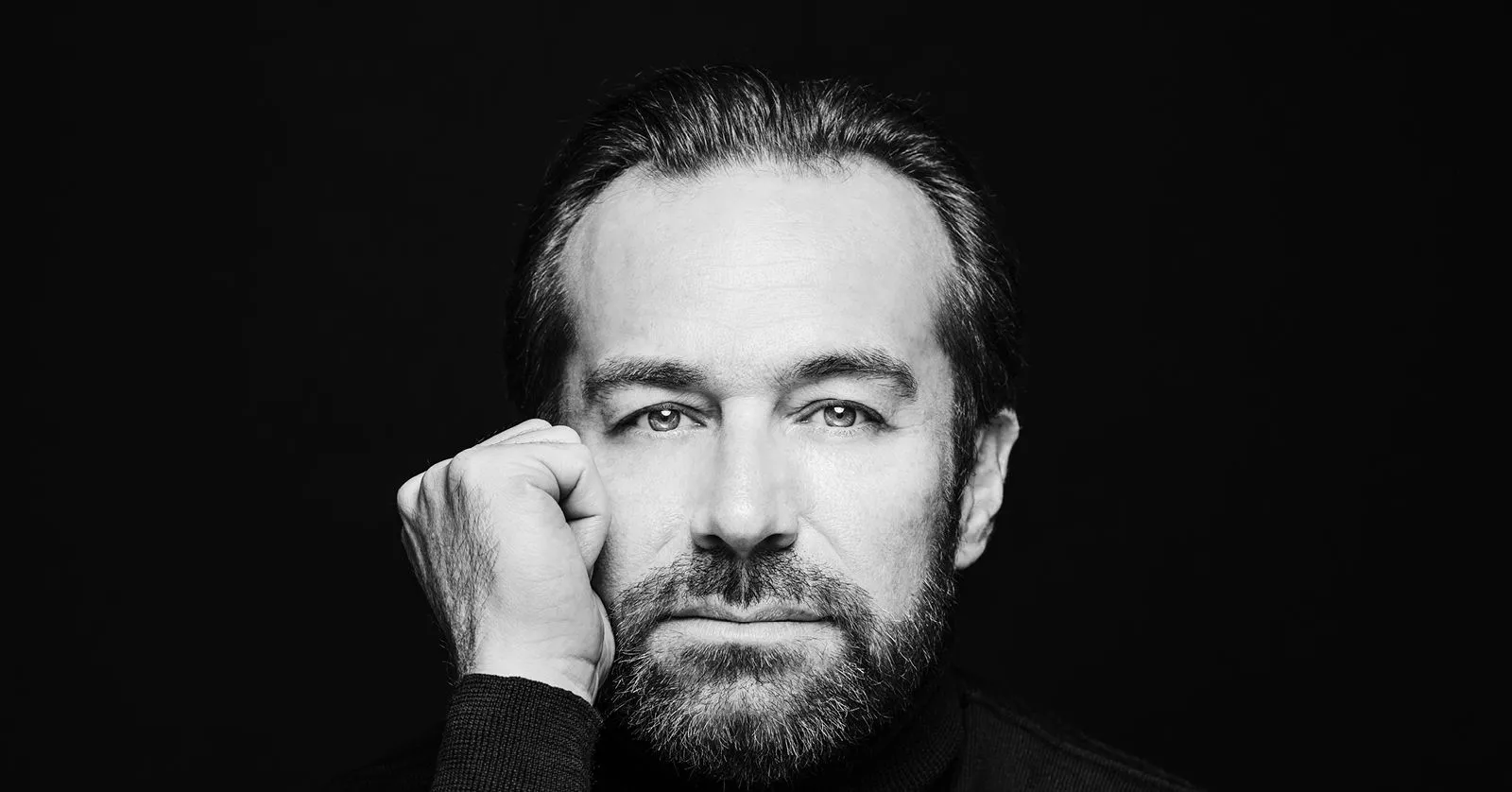 A imagem mostra Fabien Gabel, um homem branco, de cabelos castanhos. Ele olha para a câmera com a mão apoiada no queixo.