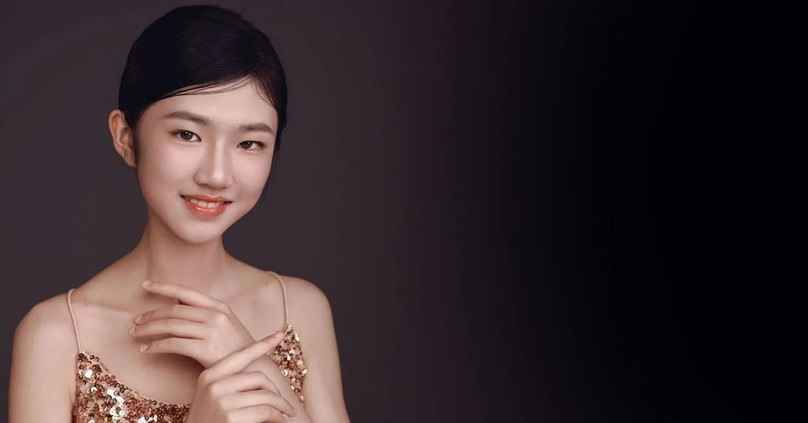 Sophia Liu é uma mulher oriental, ela usa cabelos pretos e um vestido dourado.