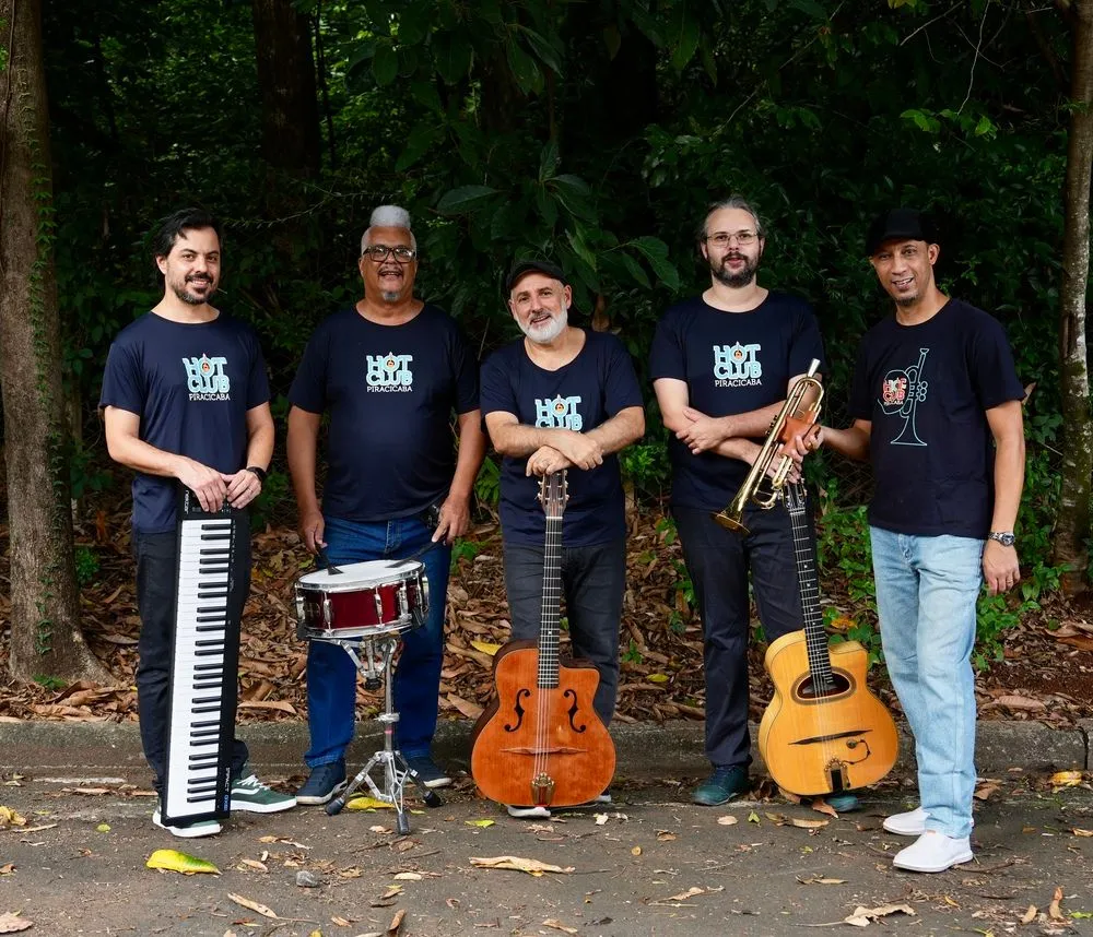 Integrantes do Hot Club Piracicaba vestem camiseta preta com logo do grupo e seguram instrumentos