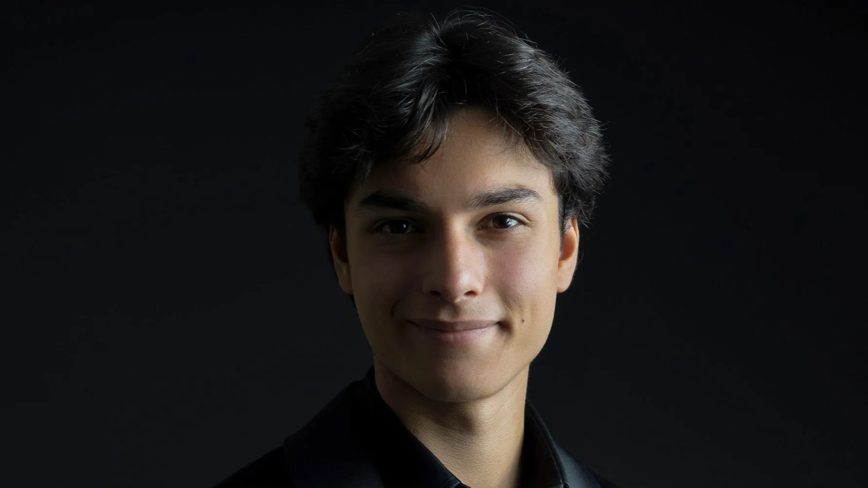 Can Saraç é um homem que veste preto e sorri.