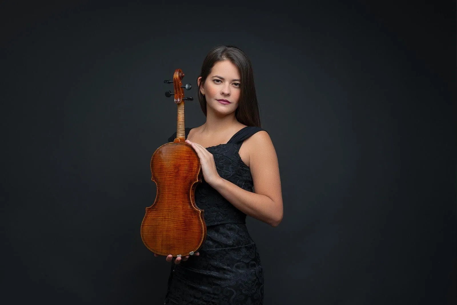 A imagem mostra um violino muito de perto, com destaque para o arco encostando nas cordas.