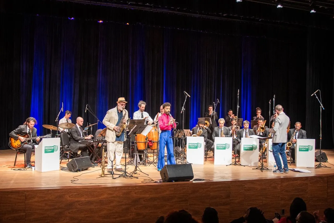 Big Band Freedom em palco. Atrás, cortinas azuis.