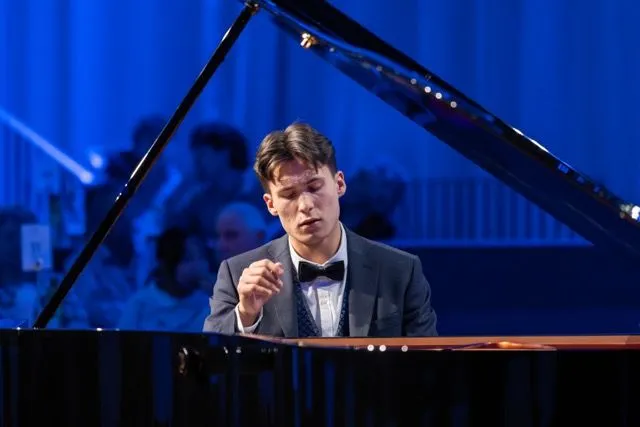 Máximo Klyetsun, um homem branco de cabelo liso repartido ao meio tocando piano.