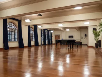 A Sala Carlos Gomes tem piso de madeira, várias luzes espalhadas pelo teto e grandes janelas com cortinas azul marinho.