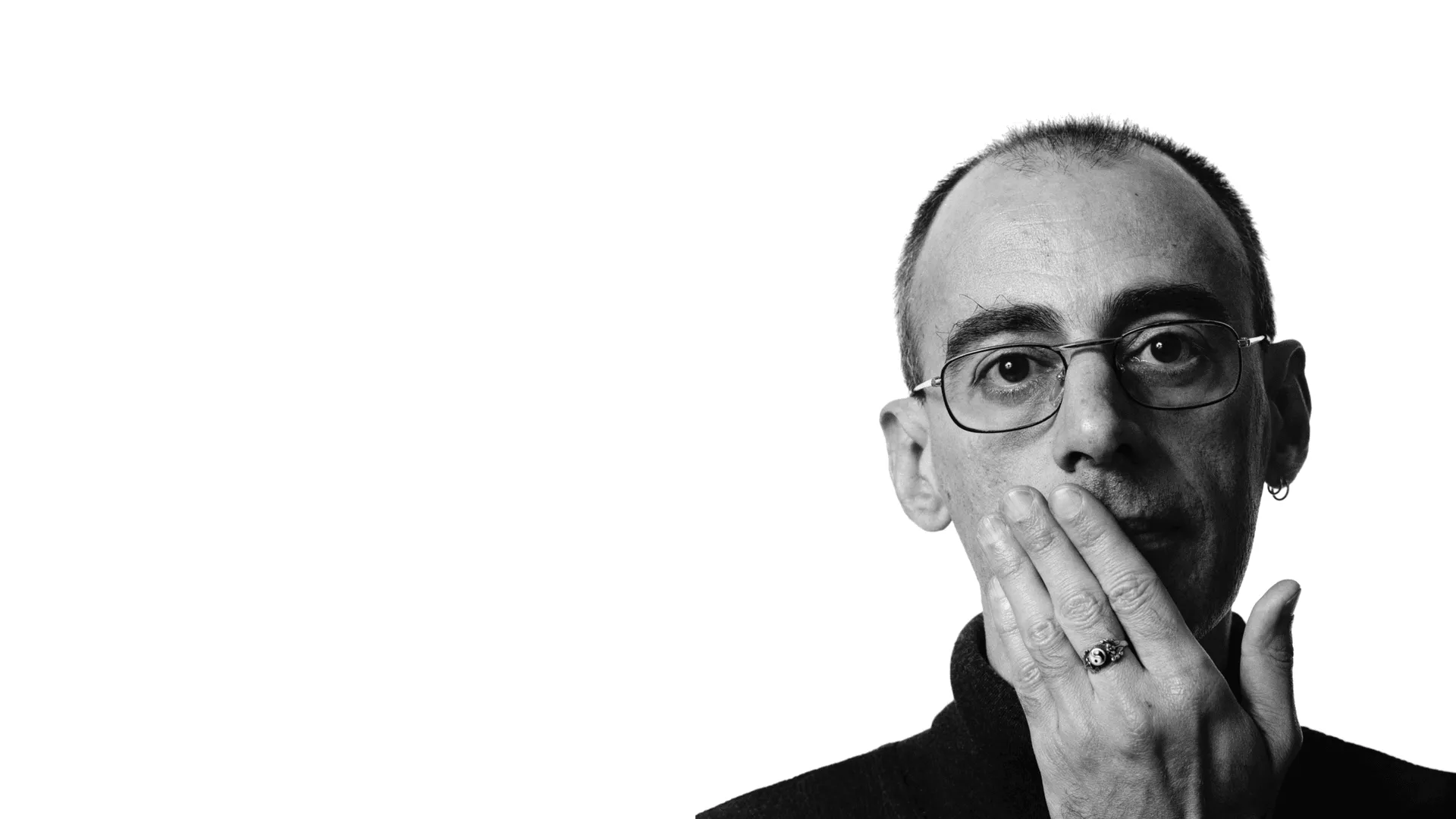 Foto em preto e branco do autor Caio Fernando de Abreu com a mão em seu rosto, em fundo branco.